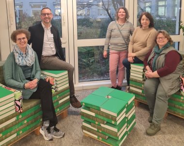 Das Team mit Dr. Fromme auf ganz besonderen Sesseln in der Landesbibliothek, gefertigt aus den Bänden des National Union-Katalogs 1956.